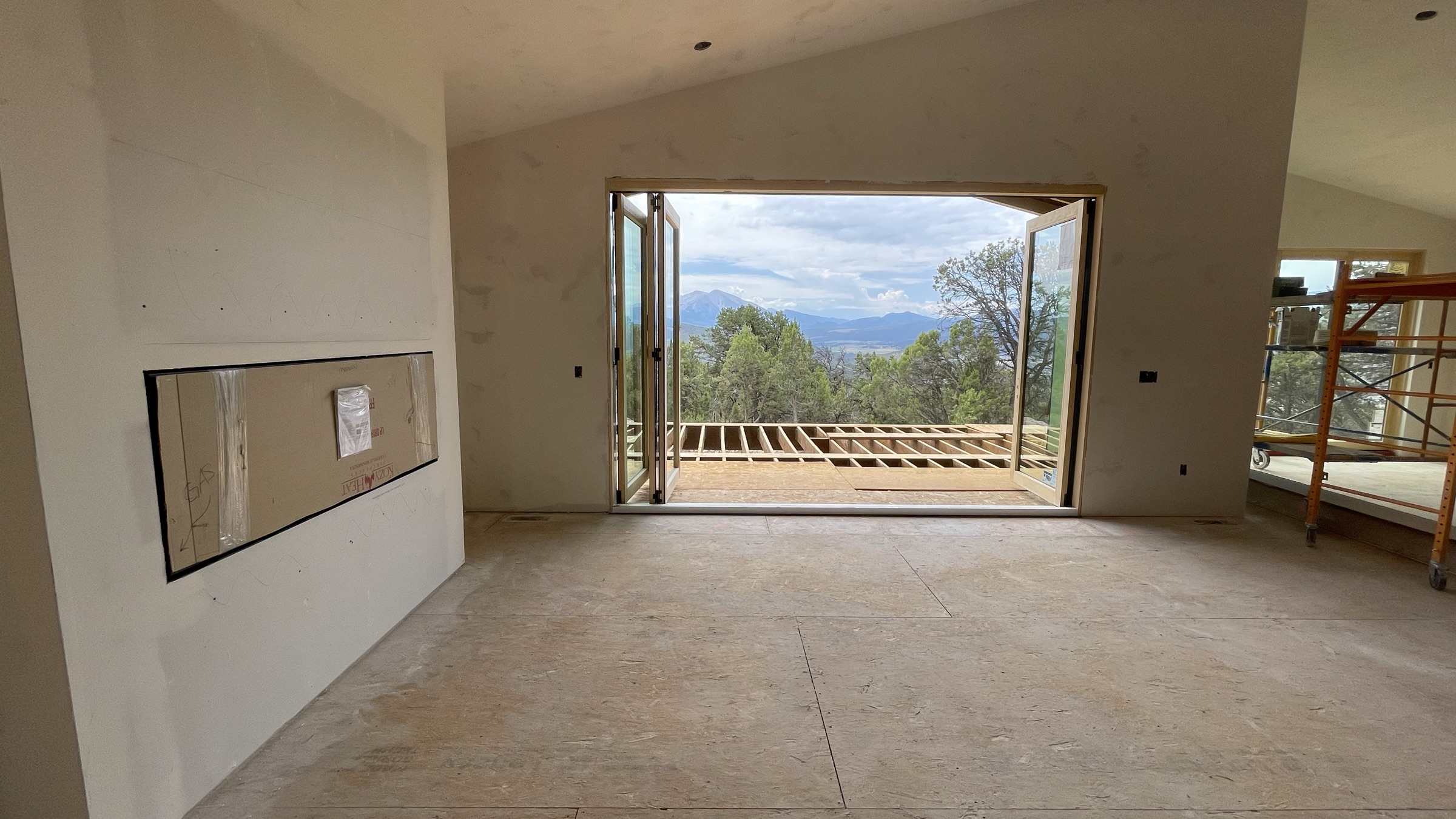 Fireplace media wall beside the open bifold door with Mt. Sopris beyond — July 26, 2026