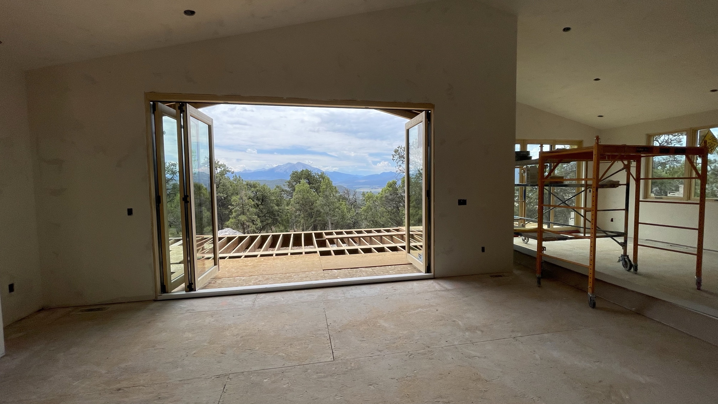 Great room with drywall complete and bifold doors open to Mt. Sopris views — July 26, 2026
