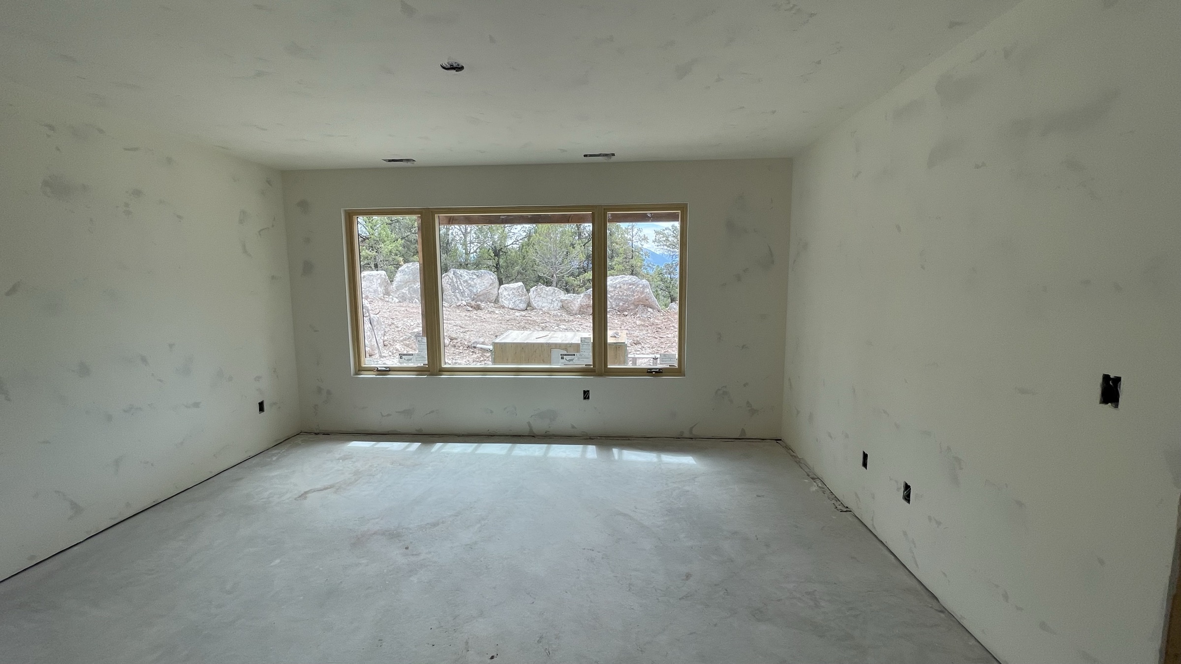 Lower level bedroom with panoramic window band, drywall complete — July 26, 2026