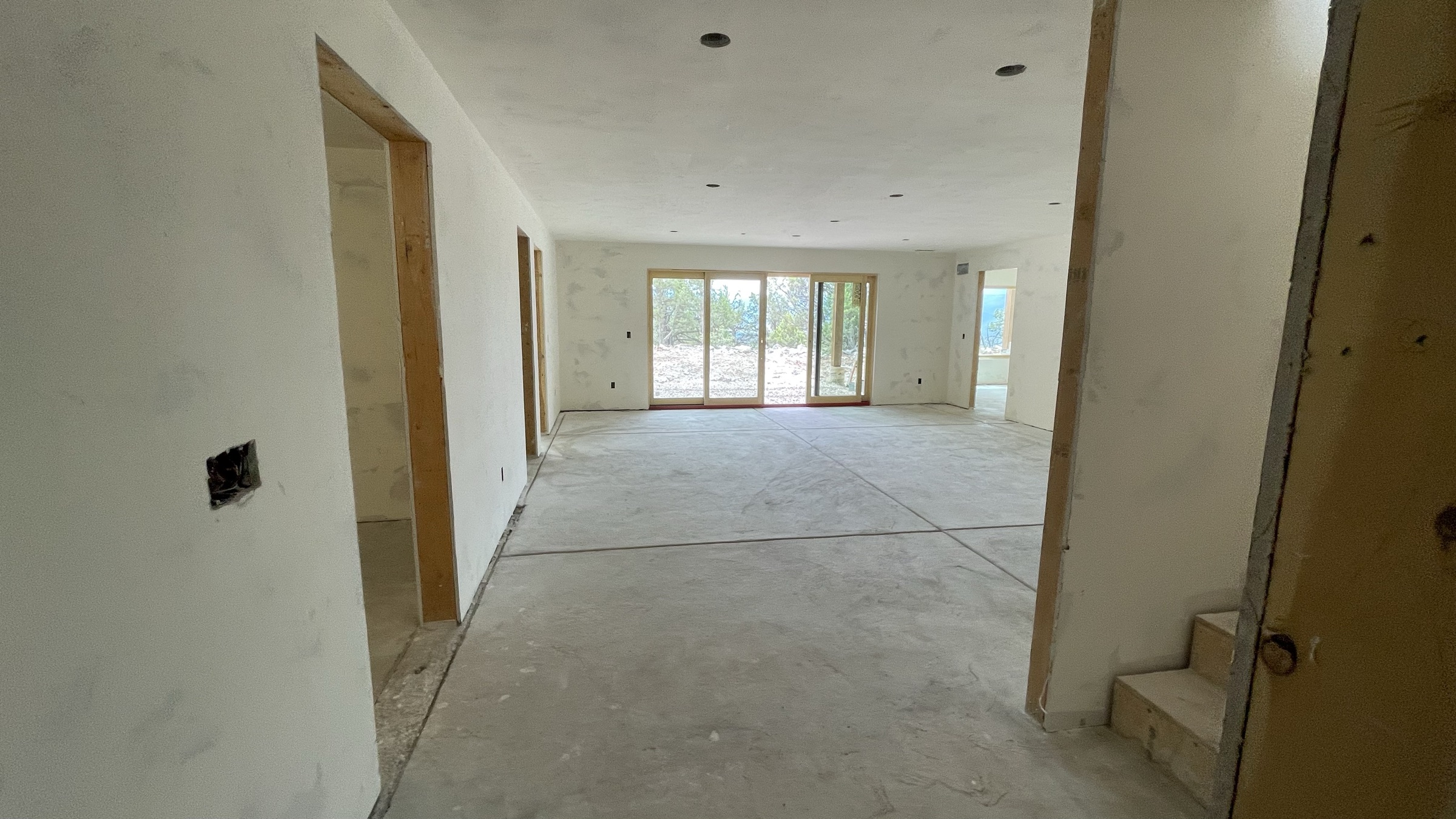 Entertainment room toward the walk-out slider, drywall complete — July 26, 2026