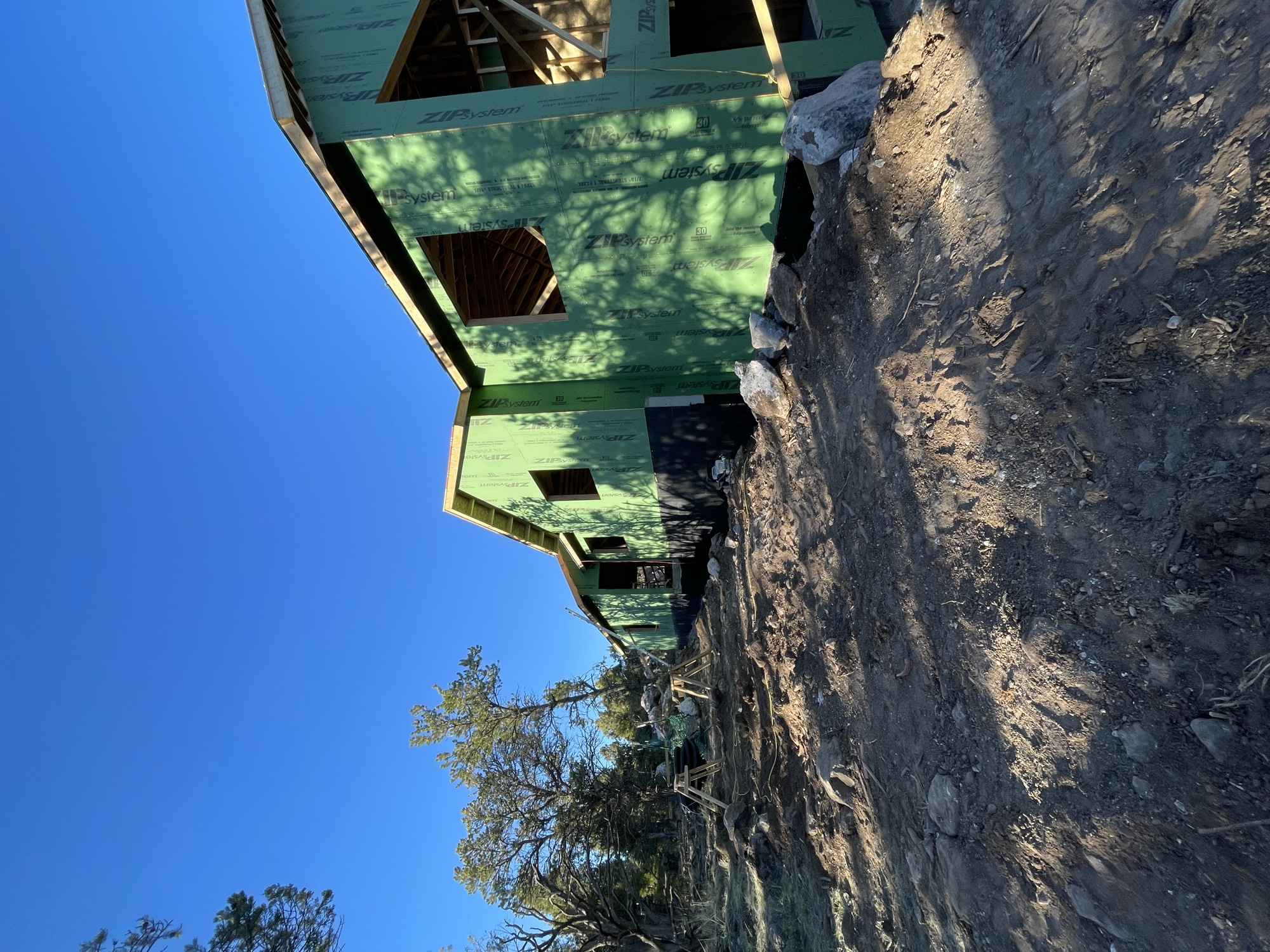 Exterior grading and site work alongside the green-sheathed structure — March 19, 2026