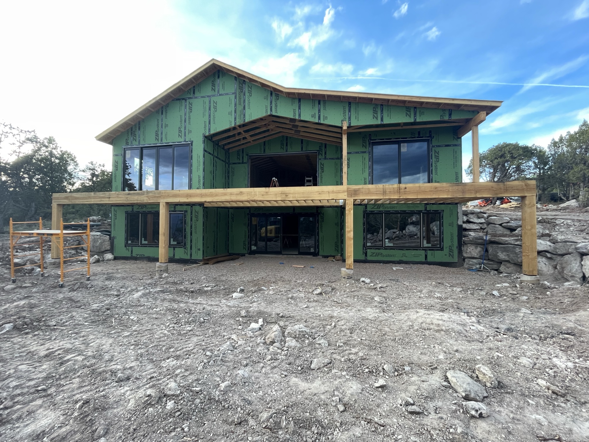 Green ZIP System exterior sheathing with pergola framing above — April 9, 2026