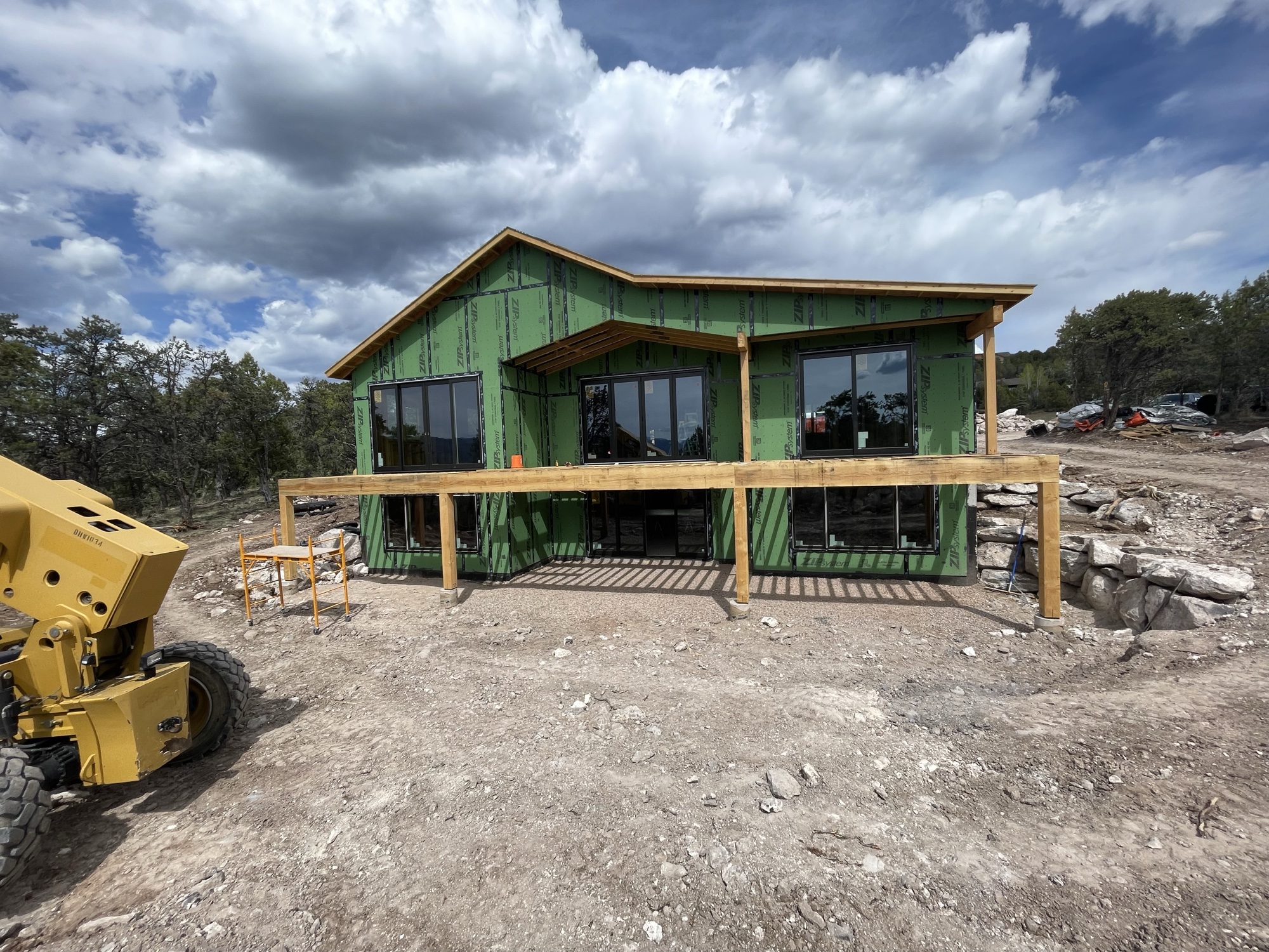 Exterior front elevation with deck framing and windows installed — April 10, 2026